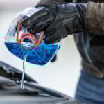 Man i handskar fyller på spolarvätska