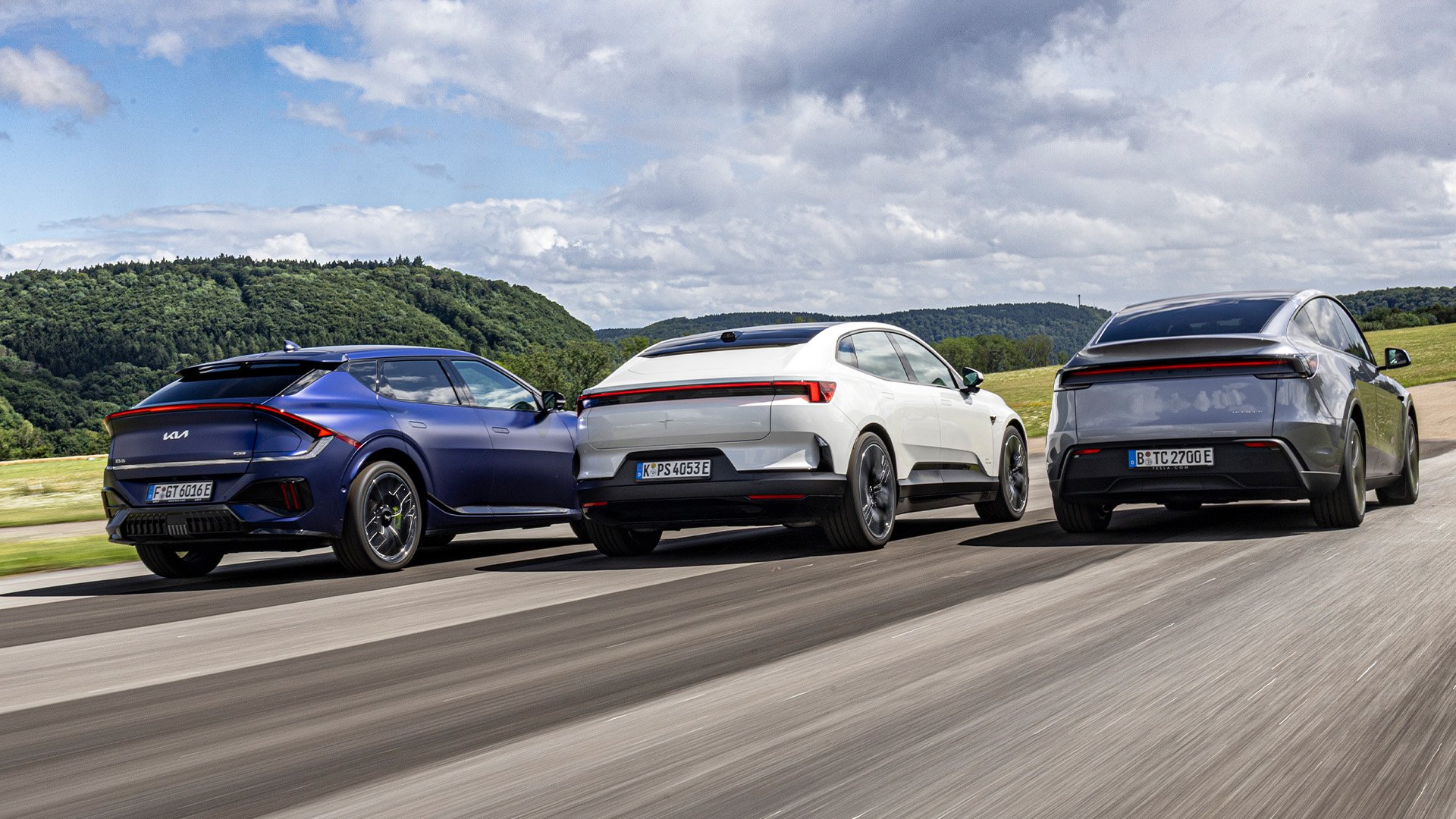Kia EV6 GT, Polestar 4, Tesla Model Y bakifrån körandes på testbana.