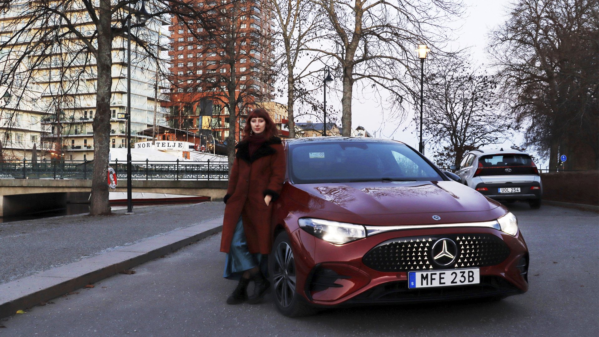 Mercedes-Benz CLA parkerad framifrån med reporter Hanna Brante vid bilen.