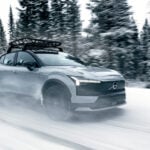 En grå Volvo EX30 Cross Country kör på snöig landsväg.