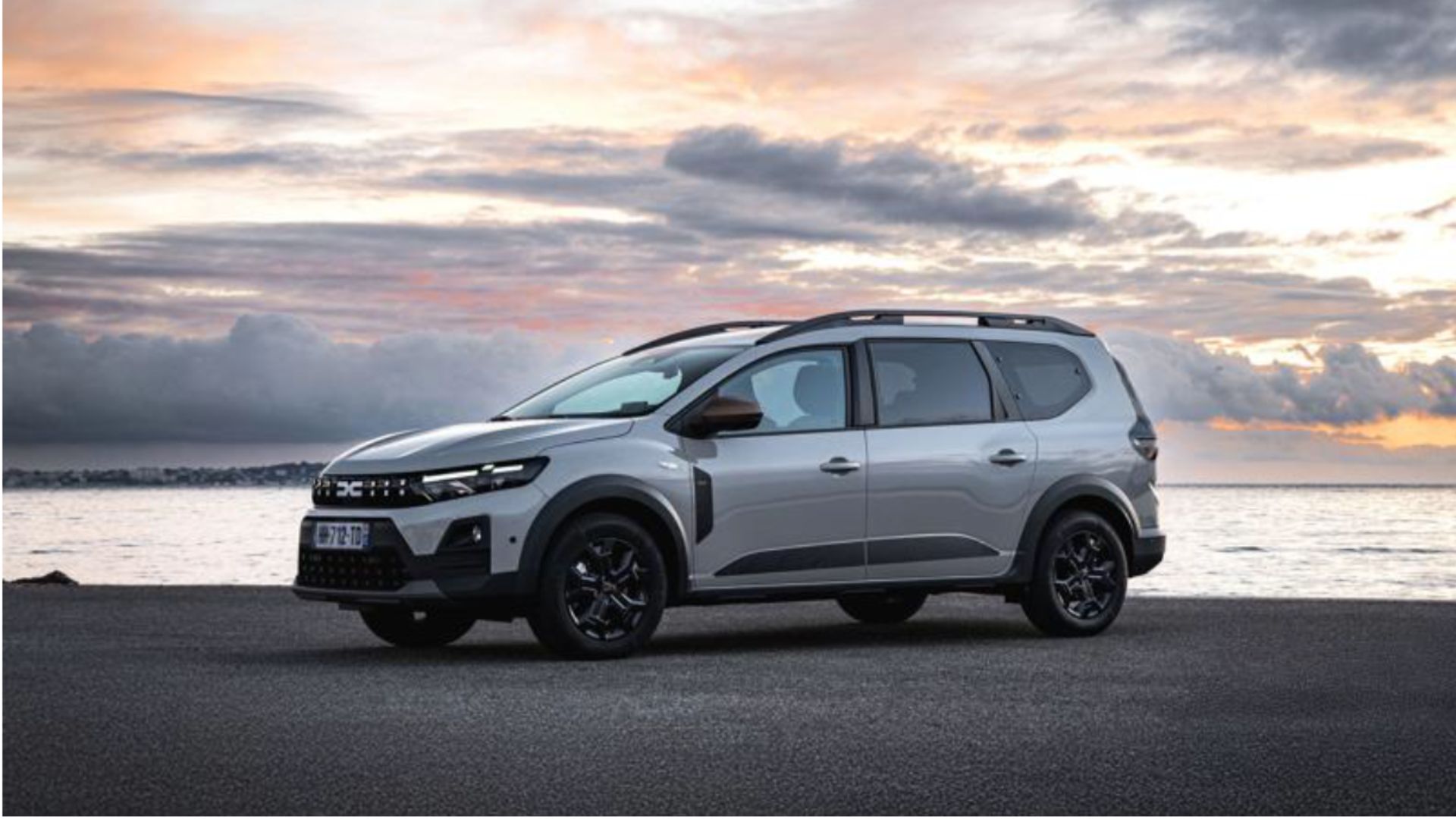 Dacia Jogger Hybrid 155 i grått sedd från sidan vid kusten