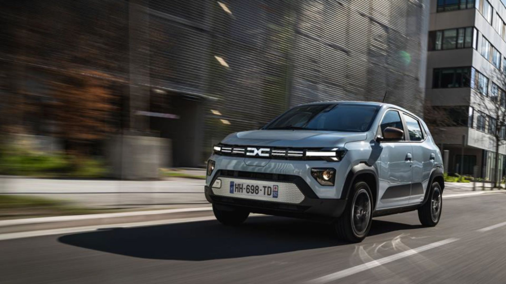 Ljusblå Dacia Spring 2026 i stadsmiljö framifrån