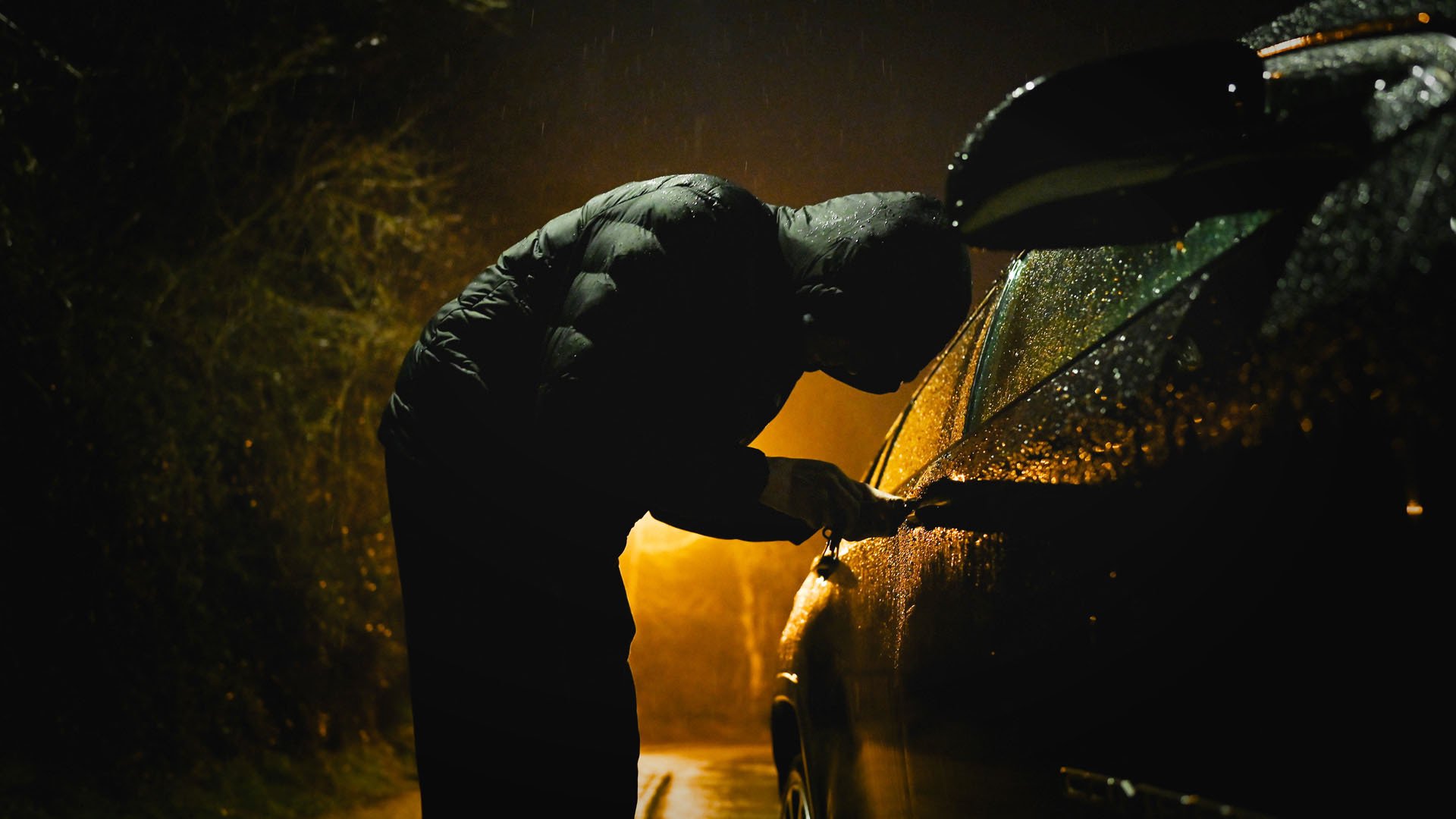 Tjuv som bryter sig in i bil.