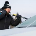 Kvinna skrapar is från bilruta. Test av isskrapor.