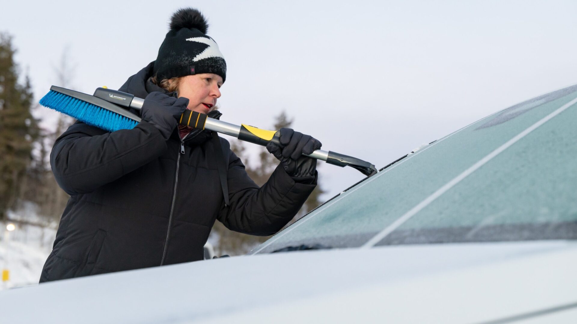 Kvinna skrapar is från bilruta. Test av isskrapor.