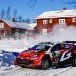 Oliver Solberg och kartläsaren Elliott Edmondson kommer körande framför ett falurött hus
