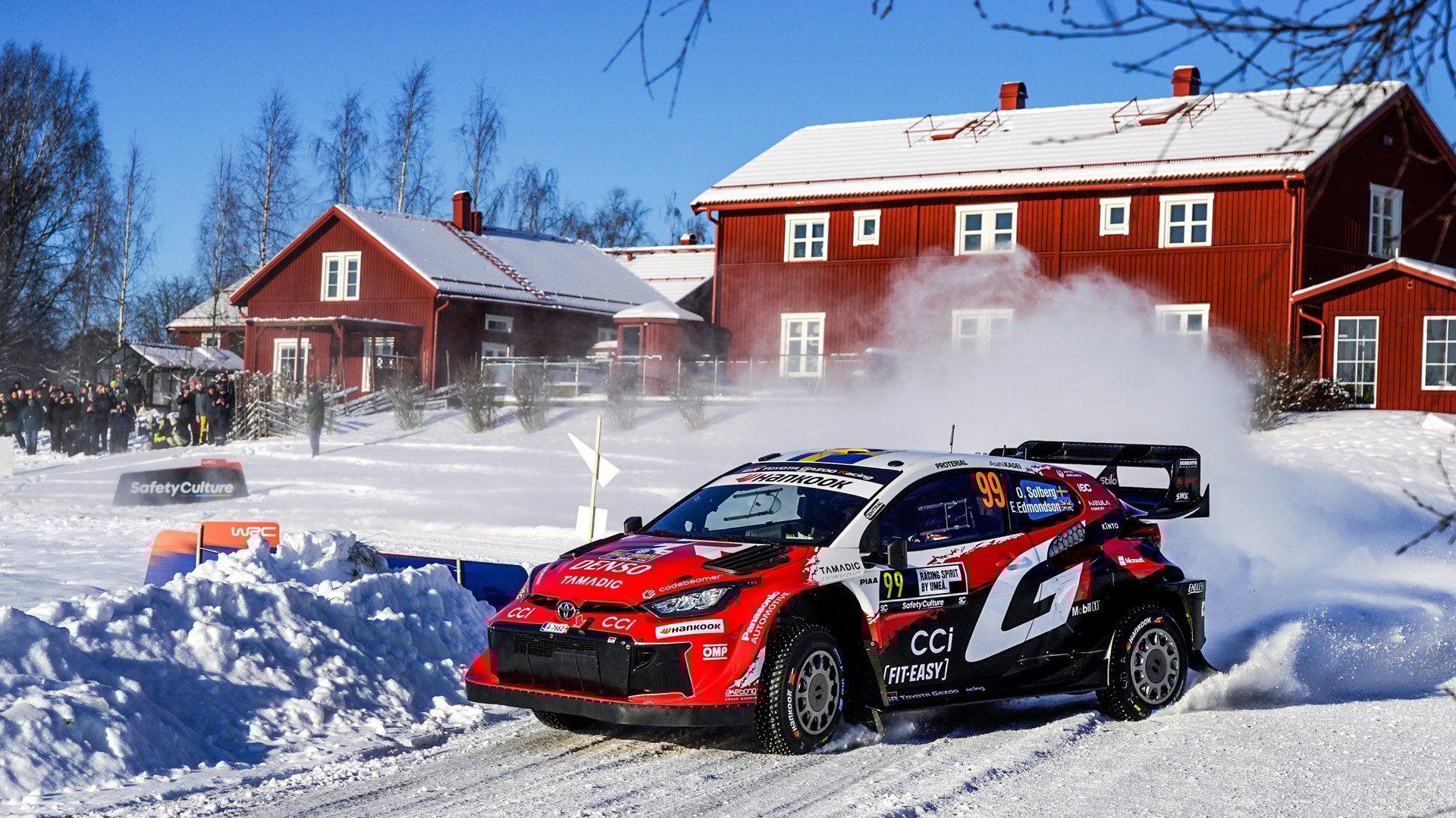 Oliver Solberg och kartläsaren Elliott Edmondson kommer körande framför ett falurött hus