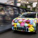 Skoda Epiq snett framifrån på en bro mitt i en stad.