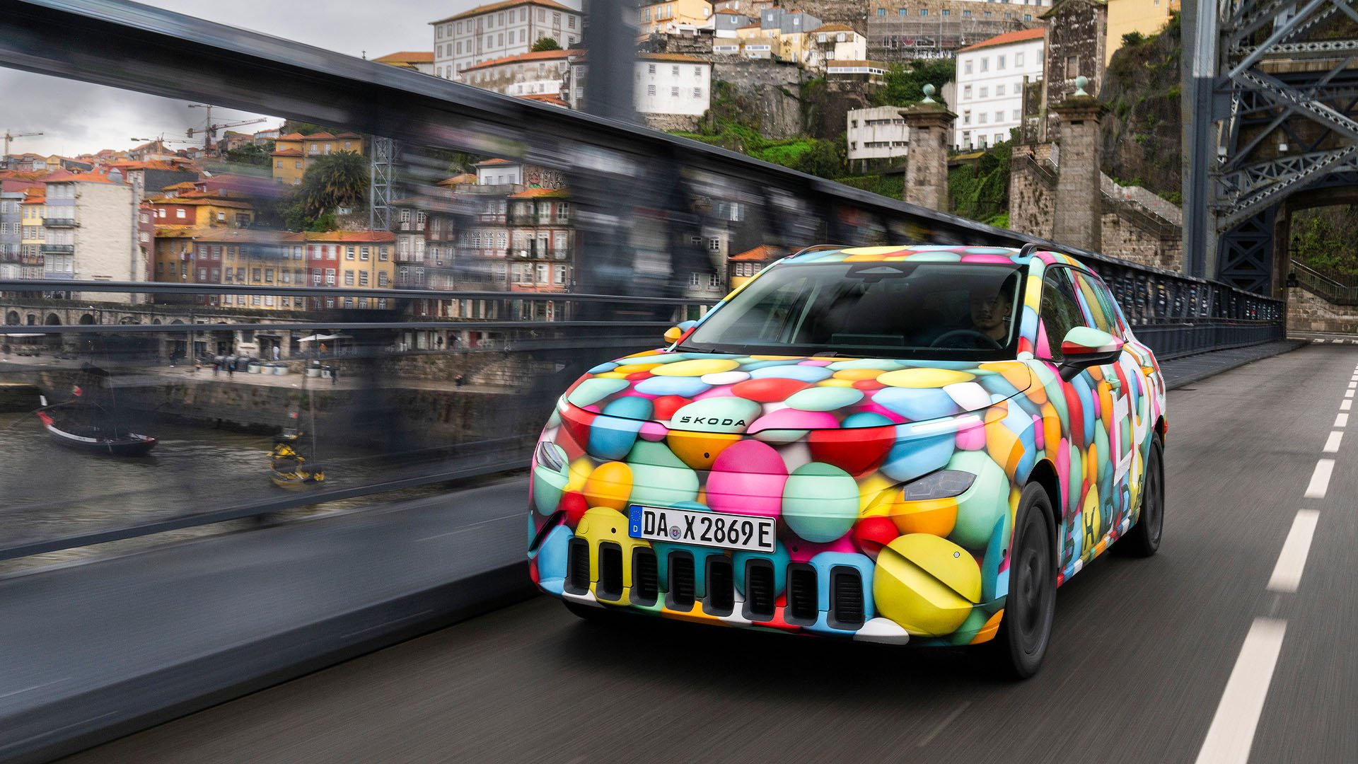 Skoda Epiq snett framifrån på en bro mitt i en stad.