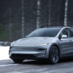 Grå Tesla Model Y kör på snöig landsväg.