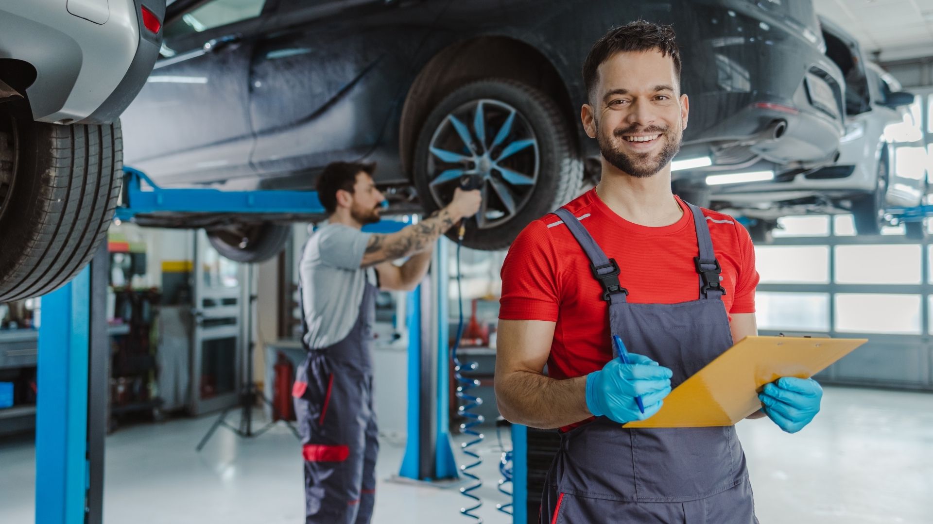 Två mekaniker arbetar med däckbyte i verkstad