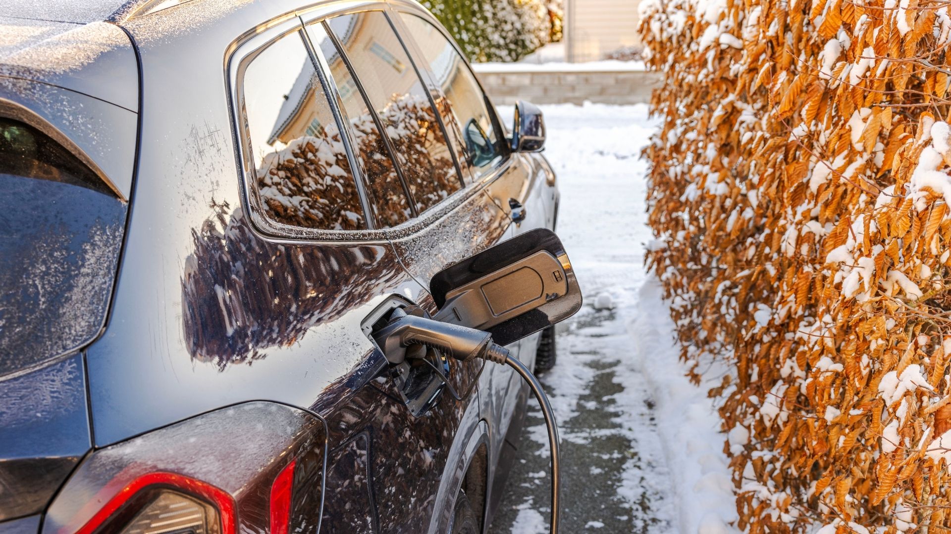 Elbil som laddas i vintermiljö utanför ett hus