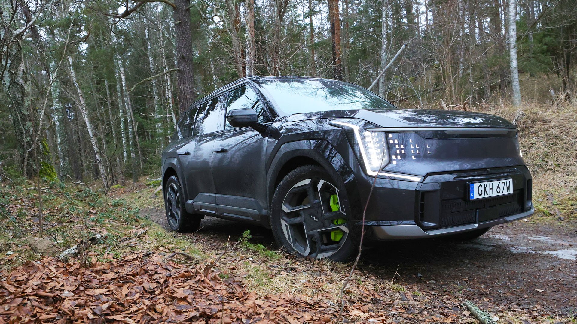 Grå Kia EV9 GT kör i terräng.