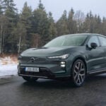 Grön Volvo EX60 i töväder på väg.