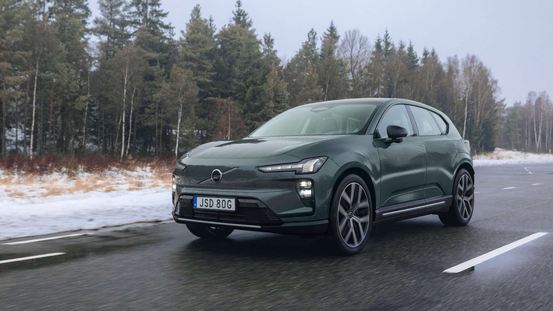 Grön Volvo EX60 i töväder på väg.