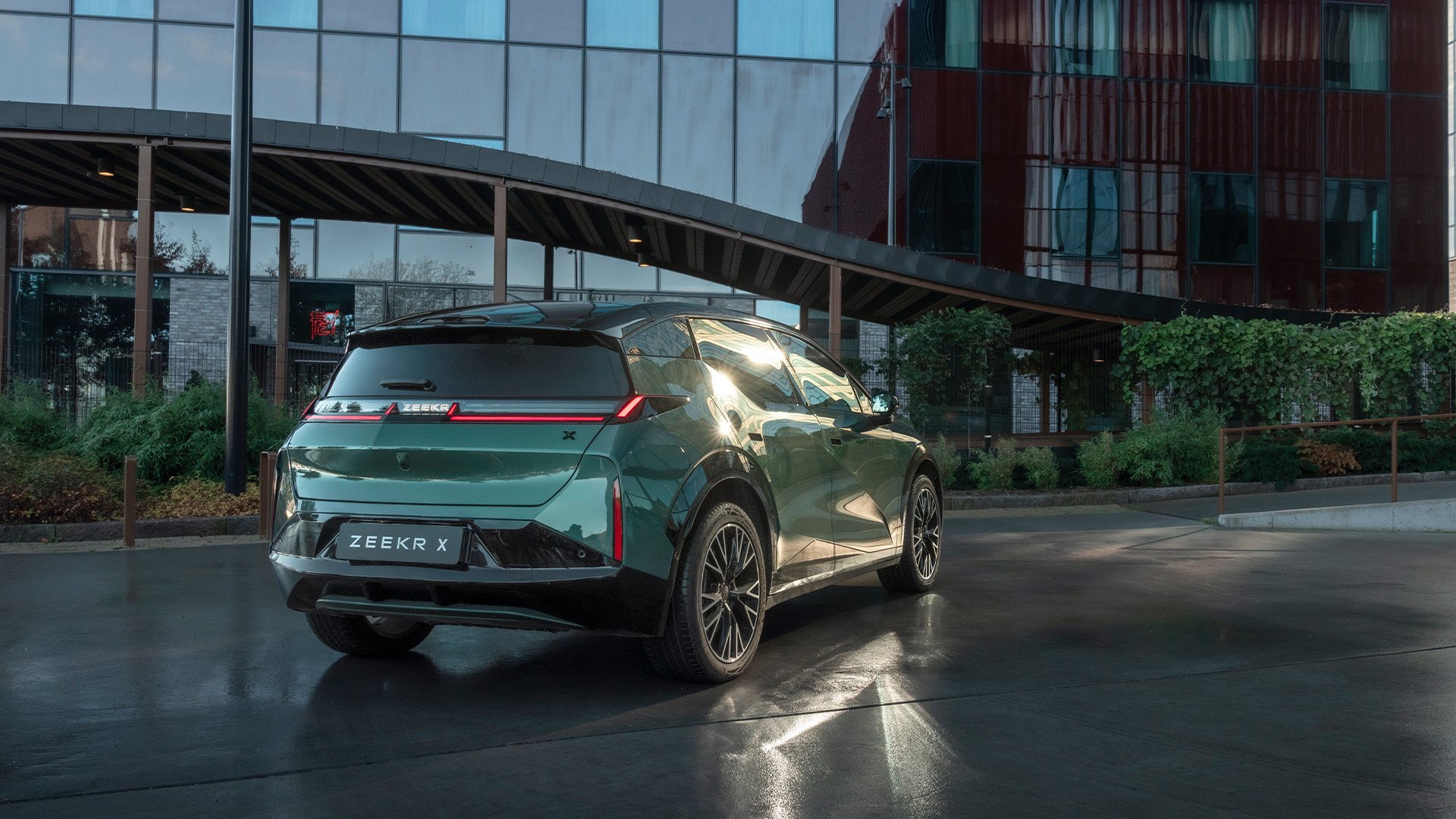 Grön Zeekr X snett bakifrån i urban miljö.