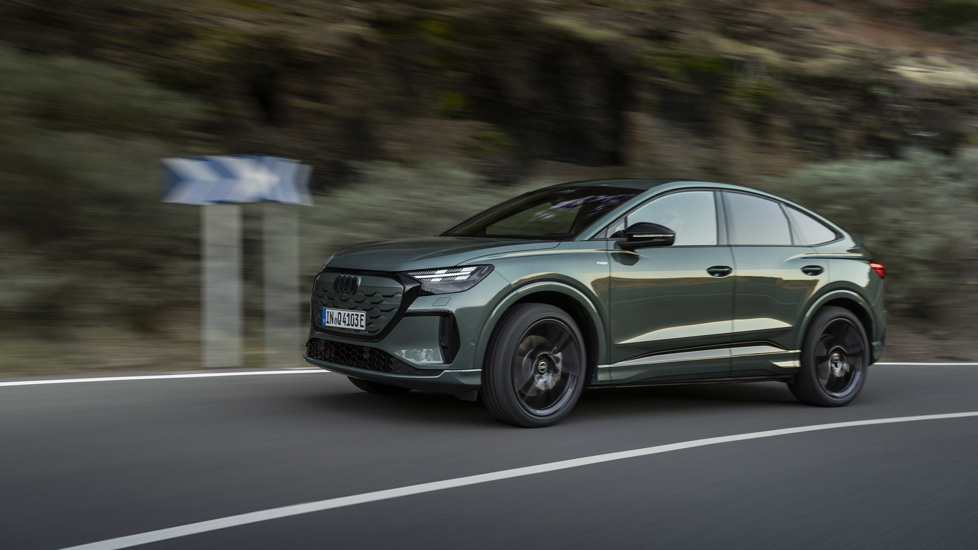 Audi Q4 e-tron Sportback snett från sidan på landsväg.