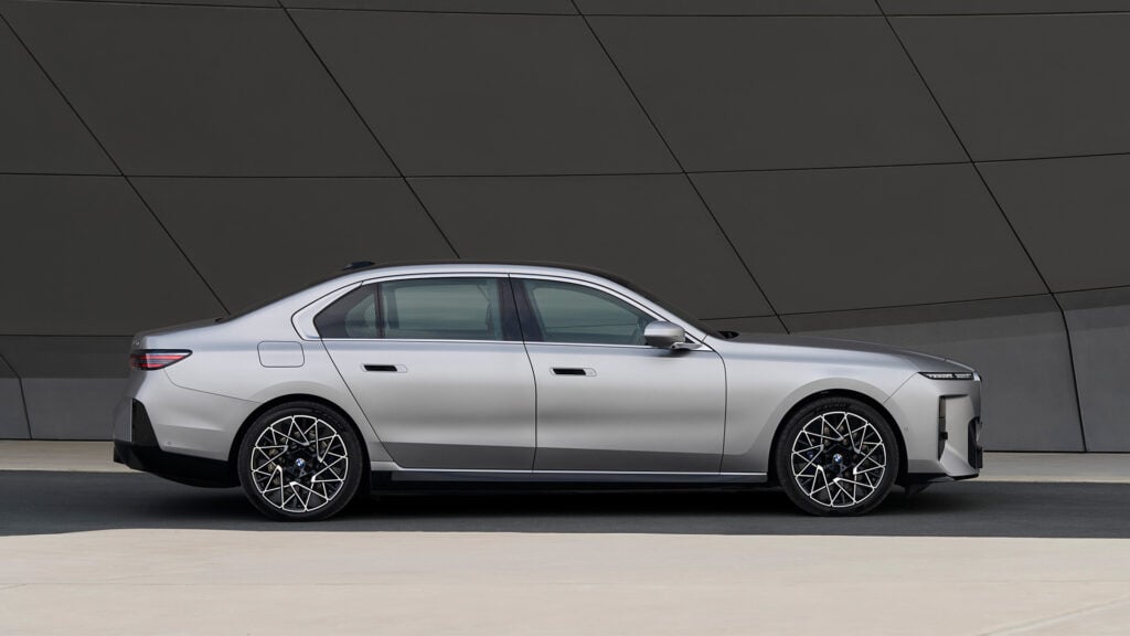 BMW 7-serien i profil framför en urban fasad.