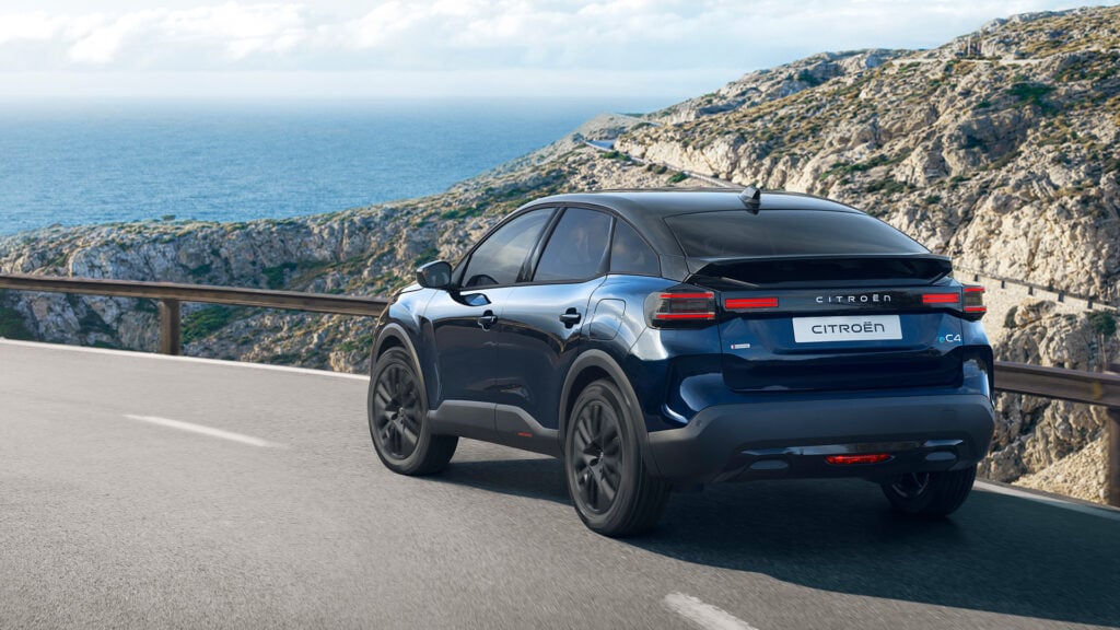 Blå Citroen C4 Collection snett bakifrån på bergsväg med hav bakom.