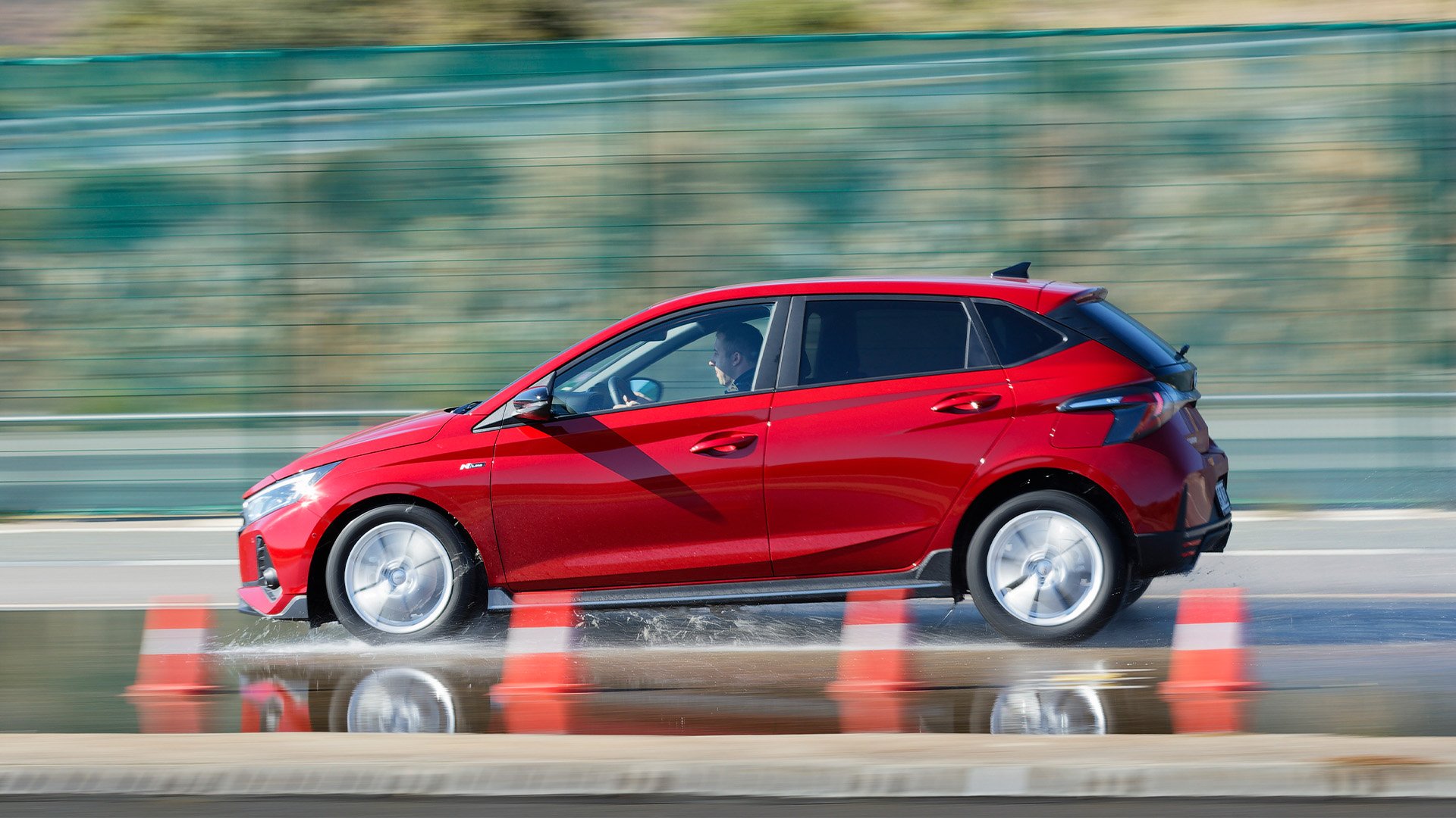 Röd Hyundai i20 i profil på testbana med koner.