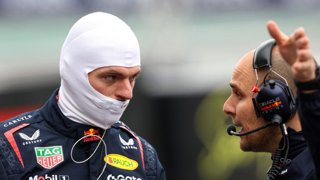 Gianpiero Lambiase till höger i bild i samspråk med Max Verstappen till vänster, med balaklava på huvudet.