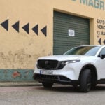 Vit Mazda CX-5 framför en beigefärgad fasad med en grön port.