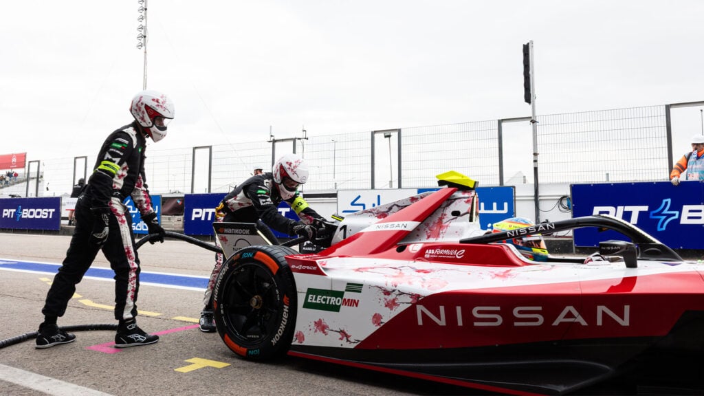 Nissan Formel E-bil med två mekaniker bakom.