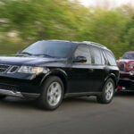 En svart Saab 9-7X drar en släpvagn med en röd Saab 93 på.