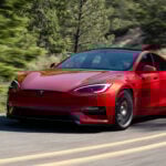 Röd Tesla Model S snett framifrån på landsväg.