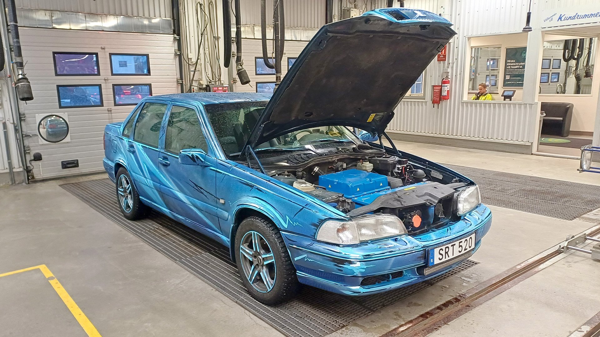 Volvo S70 som elbil med huven öppen i en besiktningshall.