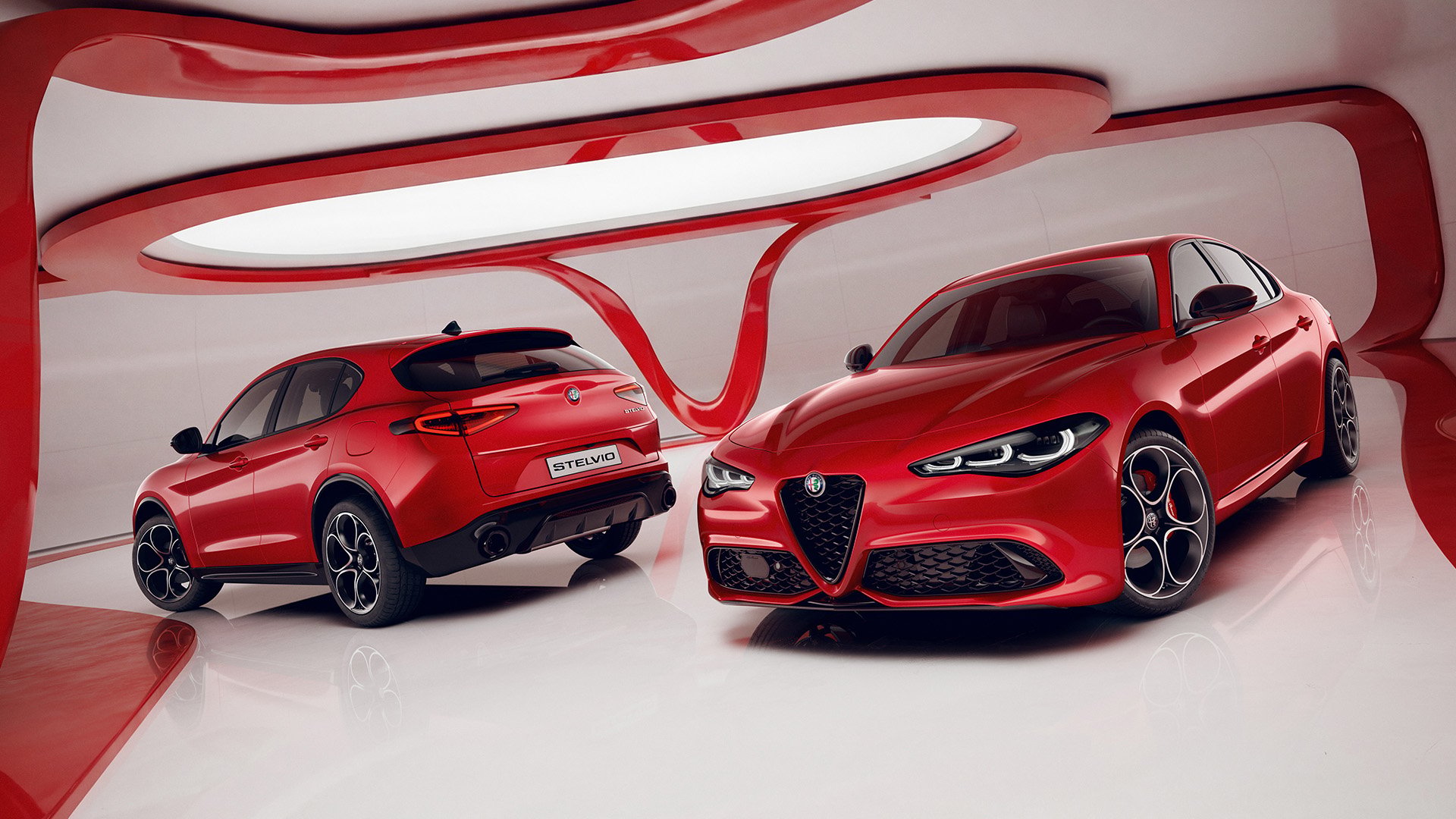 Röd Alfa Romeo Stelvio och Giulia med Pack Performance i studiomiljö.