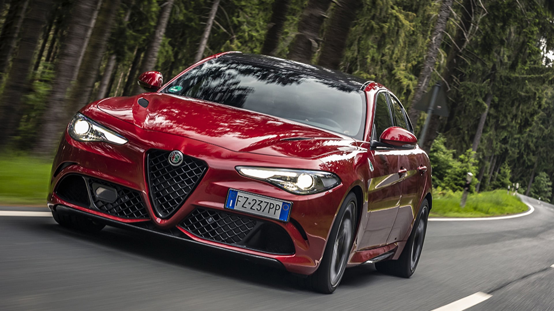 Röd Alfa Romeo Giulia på skogsväg.