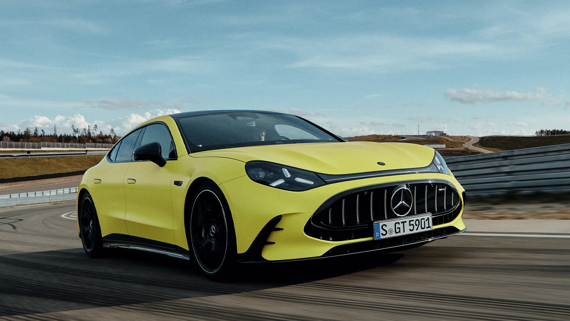 Gul Mercedes-AMG GT 4-Door Coupé snett framifrån på bana.