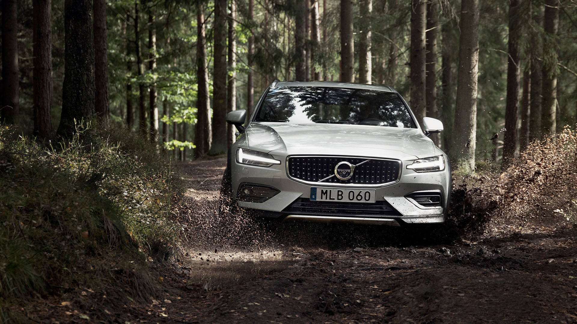 Silver Volvo V60 Cross Country sedd framifrån på skogsväg.