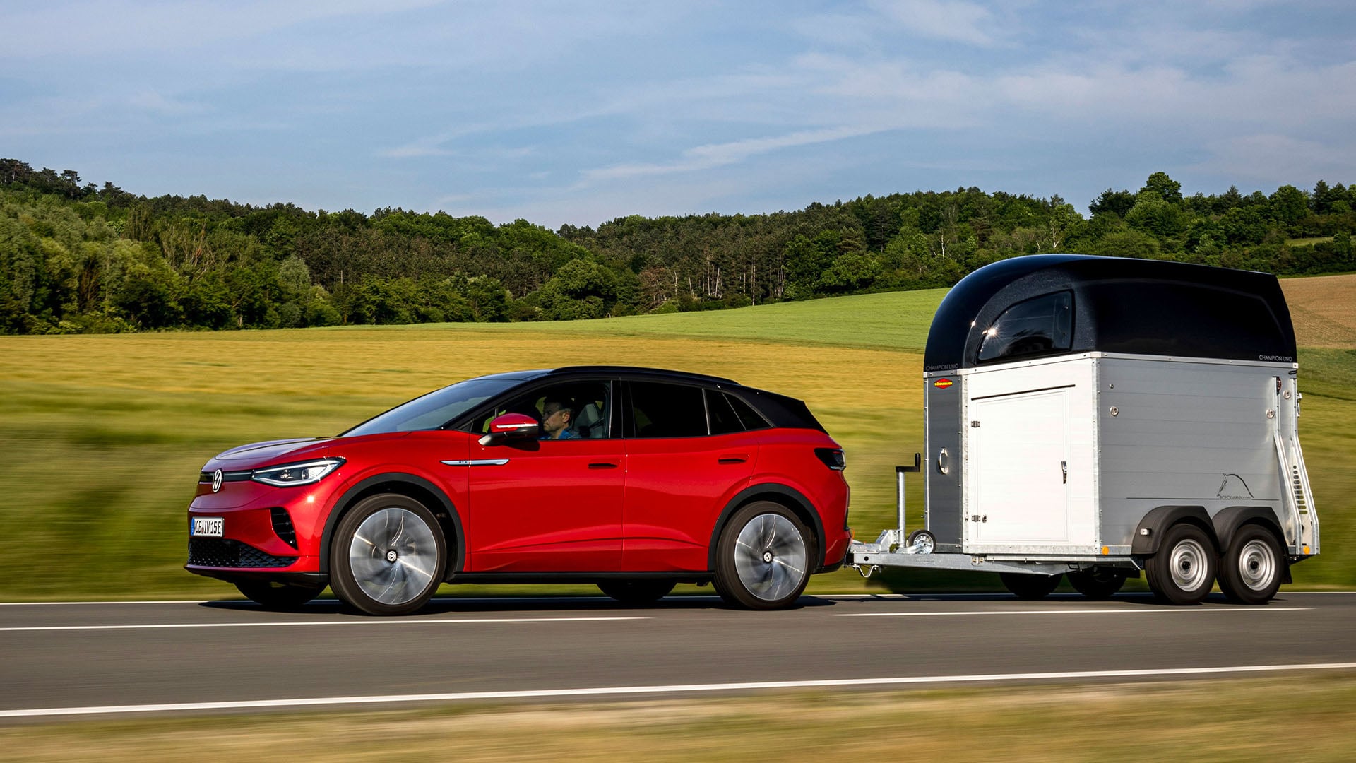 Röd Volkswagen ID.4 GTX i profil som drar på en en hästtrailer.