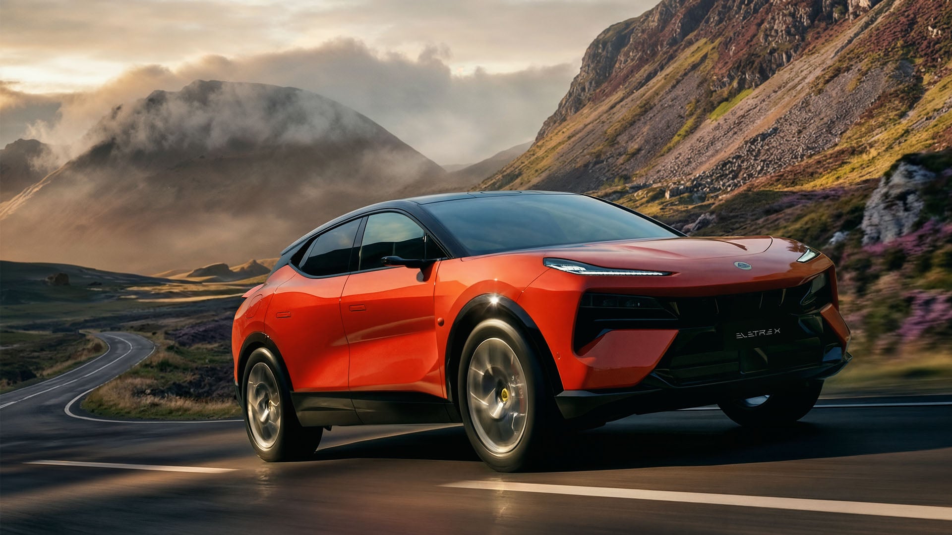 Röd Lotus Eletre X snett framifrån på en landsväg med berg i bakgrunden.