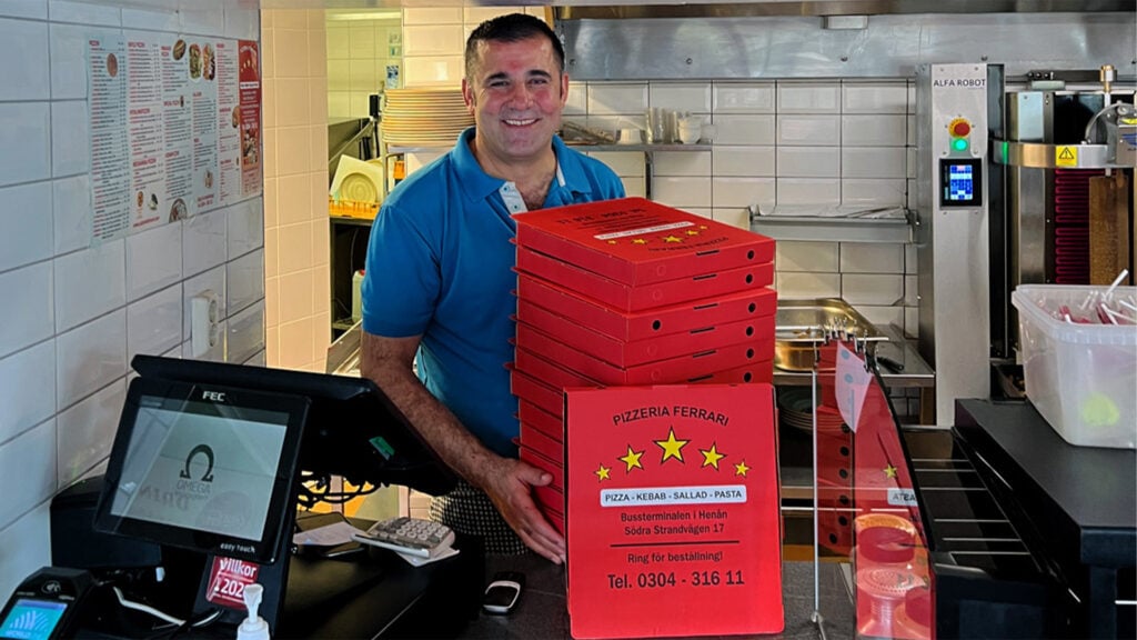 Kerim på Pizzeria Ferrari visar pizzakartonger i köket.