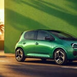 Grön Renault Twingo E-Tech i profil i solnedgången mot en grön fasad.