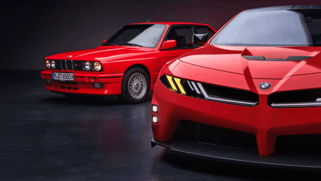 En röd BMW M Concept Neue Klasse, designstudien som visar vägen för nästa generation av den eldrivna M3, poserar sida vid sida med sin legendariska stamfader, ur-M3:an (E30). Foto: BMW