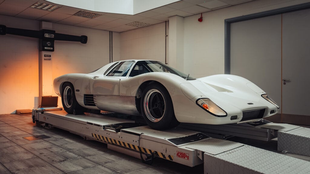 McLaren M6GT i helbild på ramp i garage.