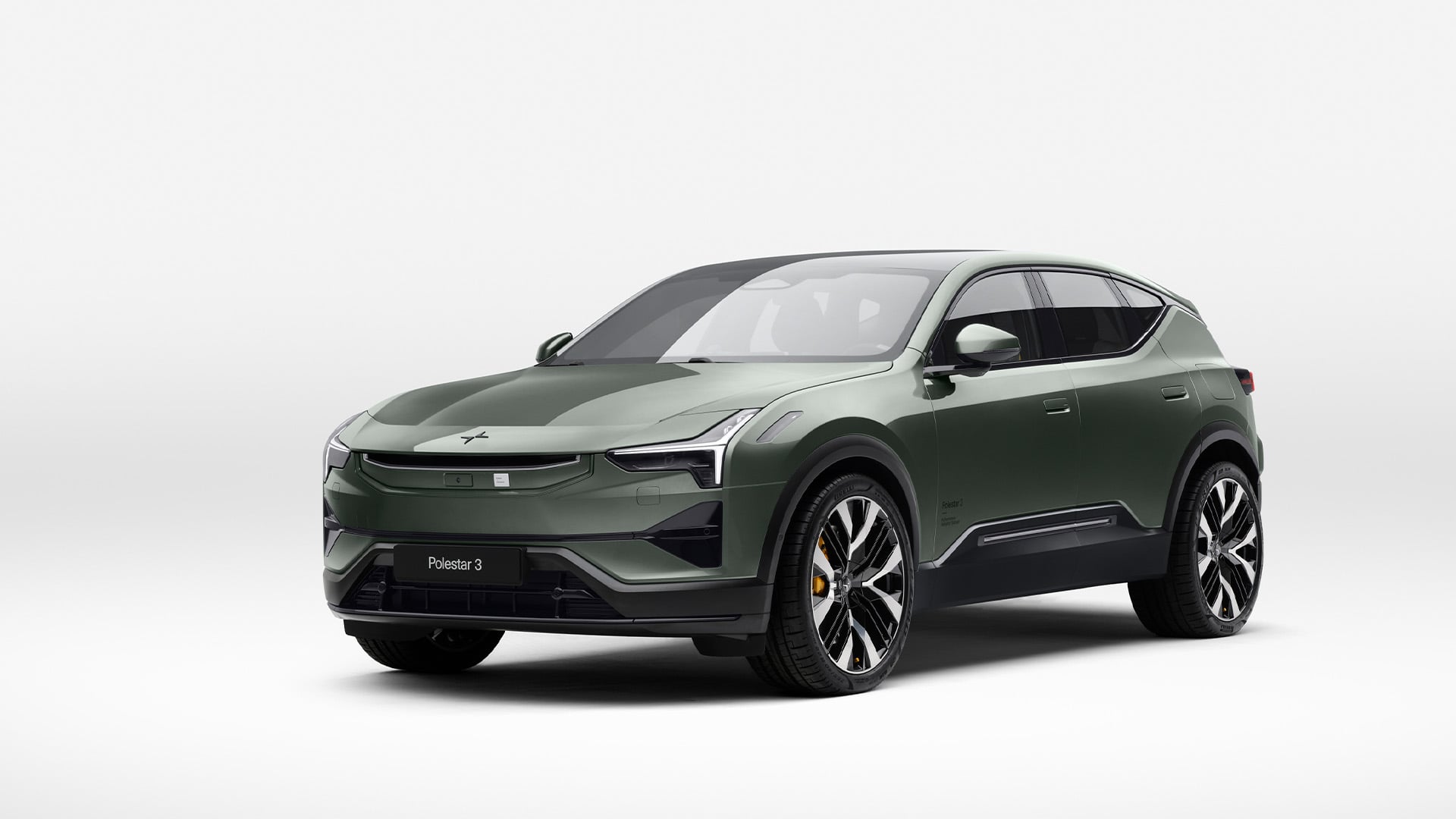 Skogsgrön Polestar 3 snett framifrån i studiomiljö.
