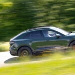 Grön Porsche Macan i profil på landsväg.
