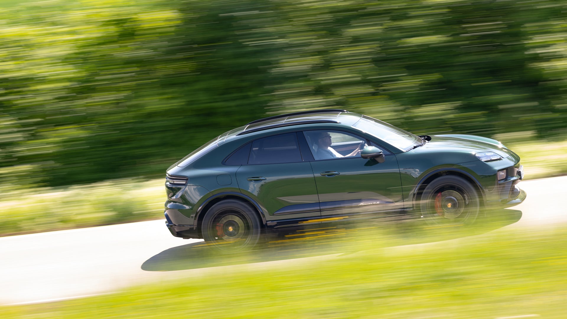 Grön Porsche Macan i profil på landsväg.