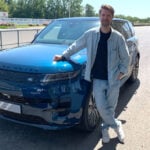 John Sempill står framför en blå Range Rover Electric Sport på Goodwood-banan.