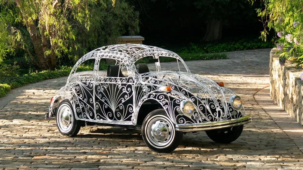 RM Sotheby’s bubbla i smidesjärn snett framifrån i stor trädgård.