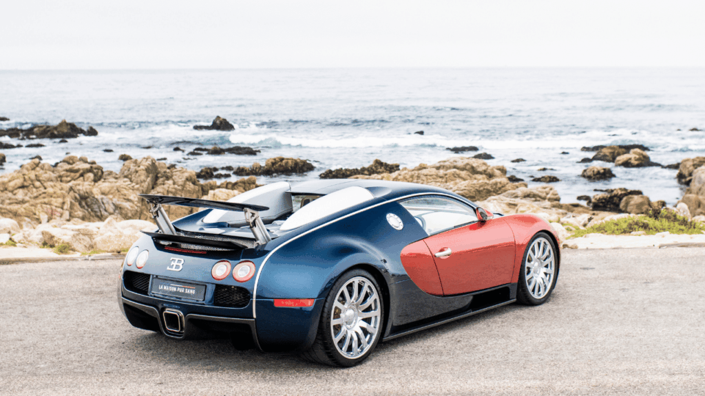 Bakifrån i trekvartsprofil: Bugatti Veyron visar upp sin muskulösa design och utfällda vinge mot kustlandskapet. Foto: Bugatti