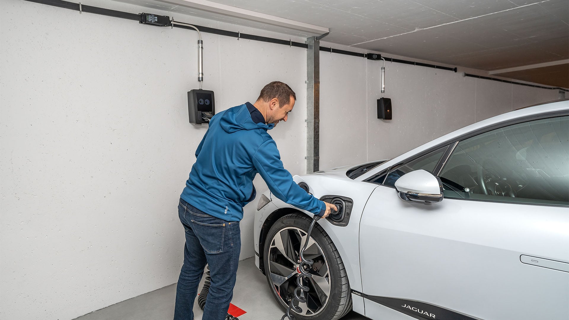 Man pluggar in laddkabel på sin Jaguar I-Pace.