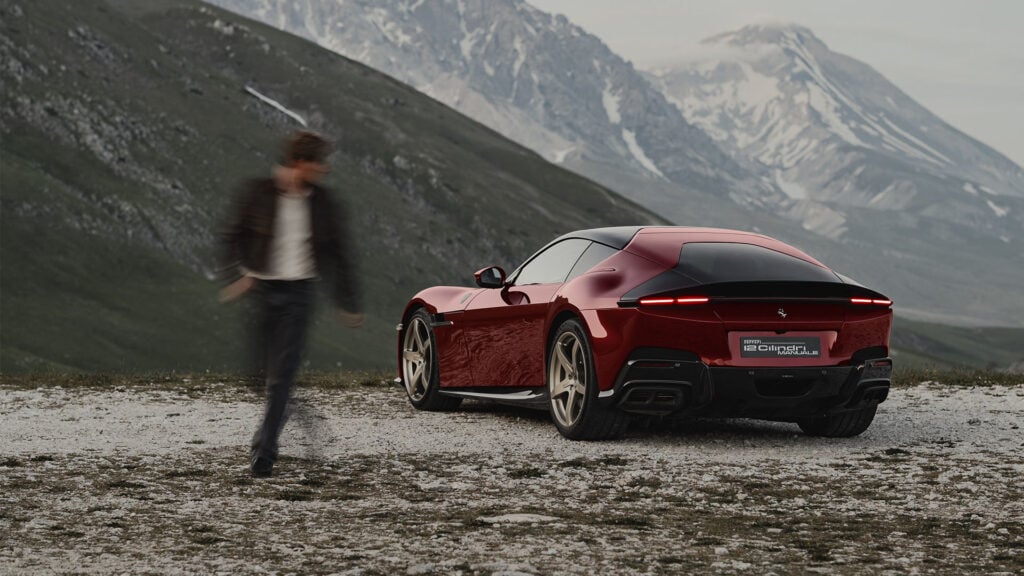 Ferrari 12Cilindri Manuale parkerad med berg i bakgrunden och en människa ur fokus som tittar på den.