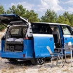 Blå Volkswagen ID. California Cruise parkerad med campingbord uppställt.