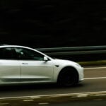 Vit Tesla Model 3 kör på landsväg.